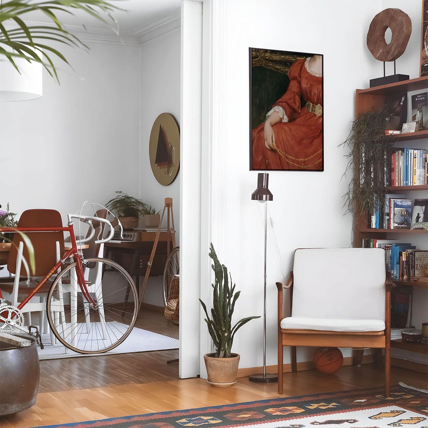 Eclectic living room with a road bike, bookshelf and house plants that features framed artwork of a Woman in the Red Dress above a chair and lamp