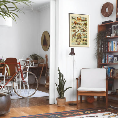 Living space with a black leather couch and table with a plant and books below a staircase featuring a framed picture of African Safari