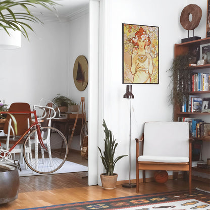 Eclectic living room with a road bike, bookshelf and house plants that features framed artwork of a Aesthetic Yellow and Pink above a chair and lamp