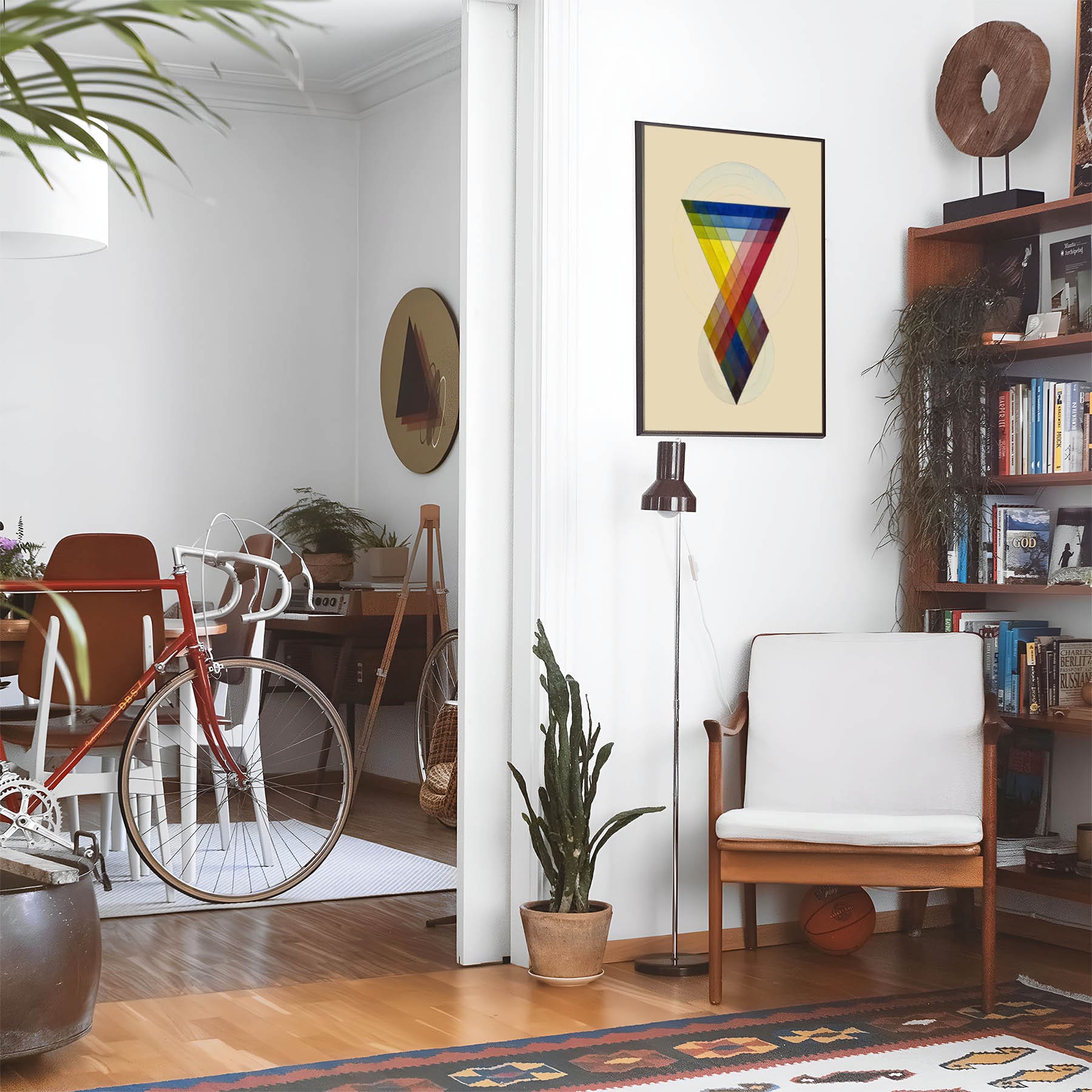 Eclectic living room with a road bike, bookshelf and house plants that features framed artwork of a Study of Colors above a chair and lamp