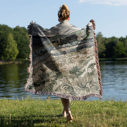 Dark Cloudy Hillside Woven Throw Blanket Held on a Woman's Back Outside