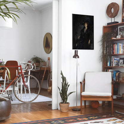 Eclectic living room with a road bike, bookshelf and house plants that features framed artwork of a Woman Dressed in Dark Blue above a chair and lamp