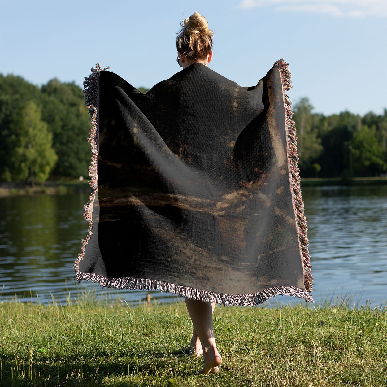 Dark Forest Woven Throw Blanket Held on a Woman's Back Outside