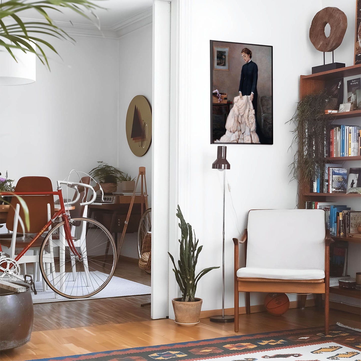 Eclectic living room with a road bike, bookshelf and house plants that features framed artwork of a Mourning Woman with a Wedding Dress above a chair and lamp