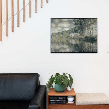 Living space with a black leather couch and table with a plant and books below a staircase featuring a framed picture of Water and Trees