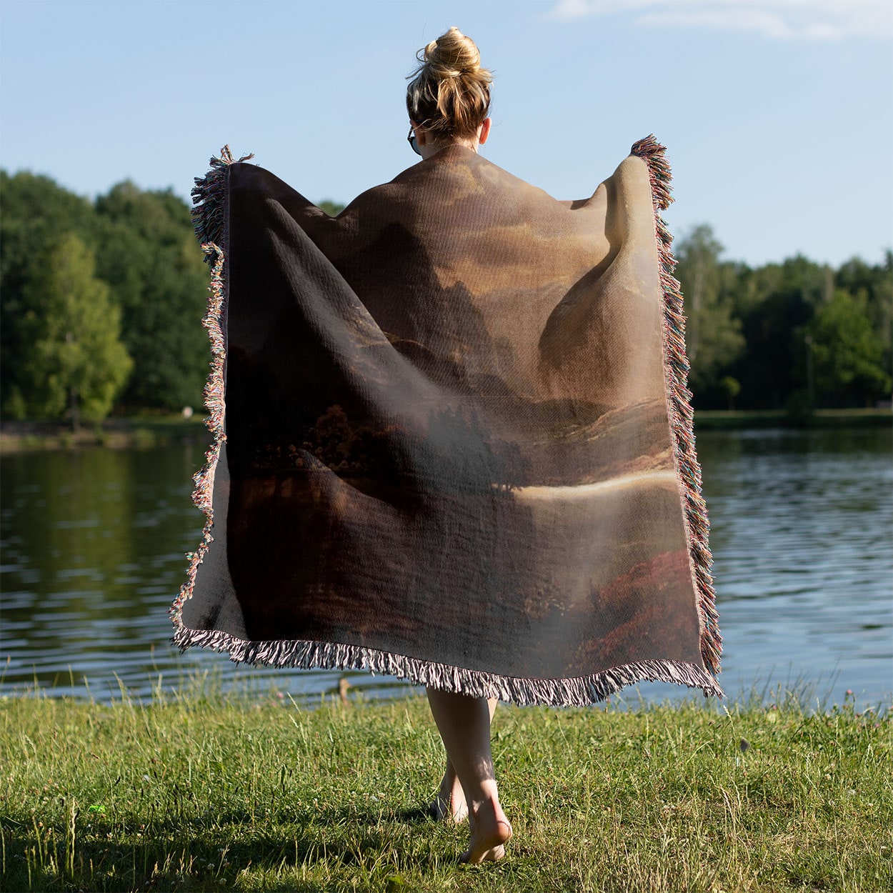 Ethereal Mountains Woven Throw Blanket Held on a Woman's Back Outside