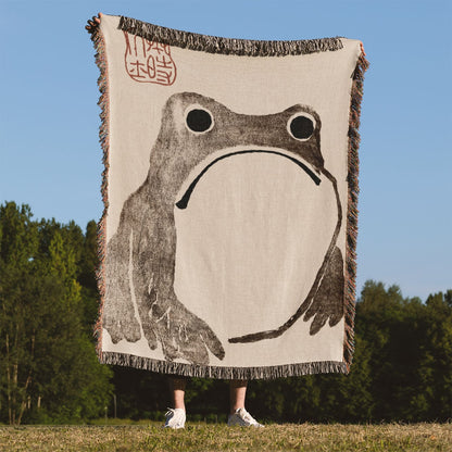 Grumpy Frog Woven Blanket Held Up Outside
