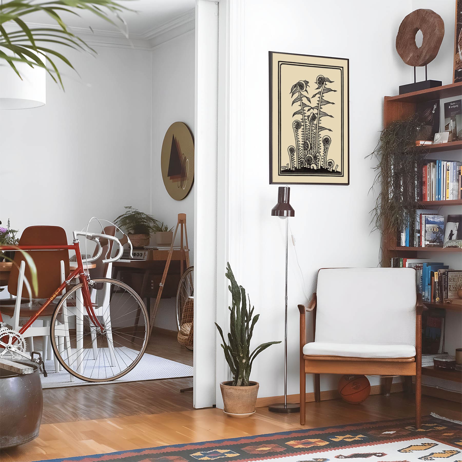Eclectic living room with a road bike, bookshelf and house plants that features framed artwork of a Black Ferns above a chair and lamp