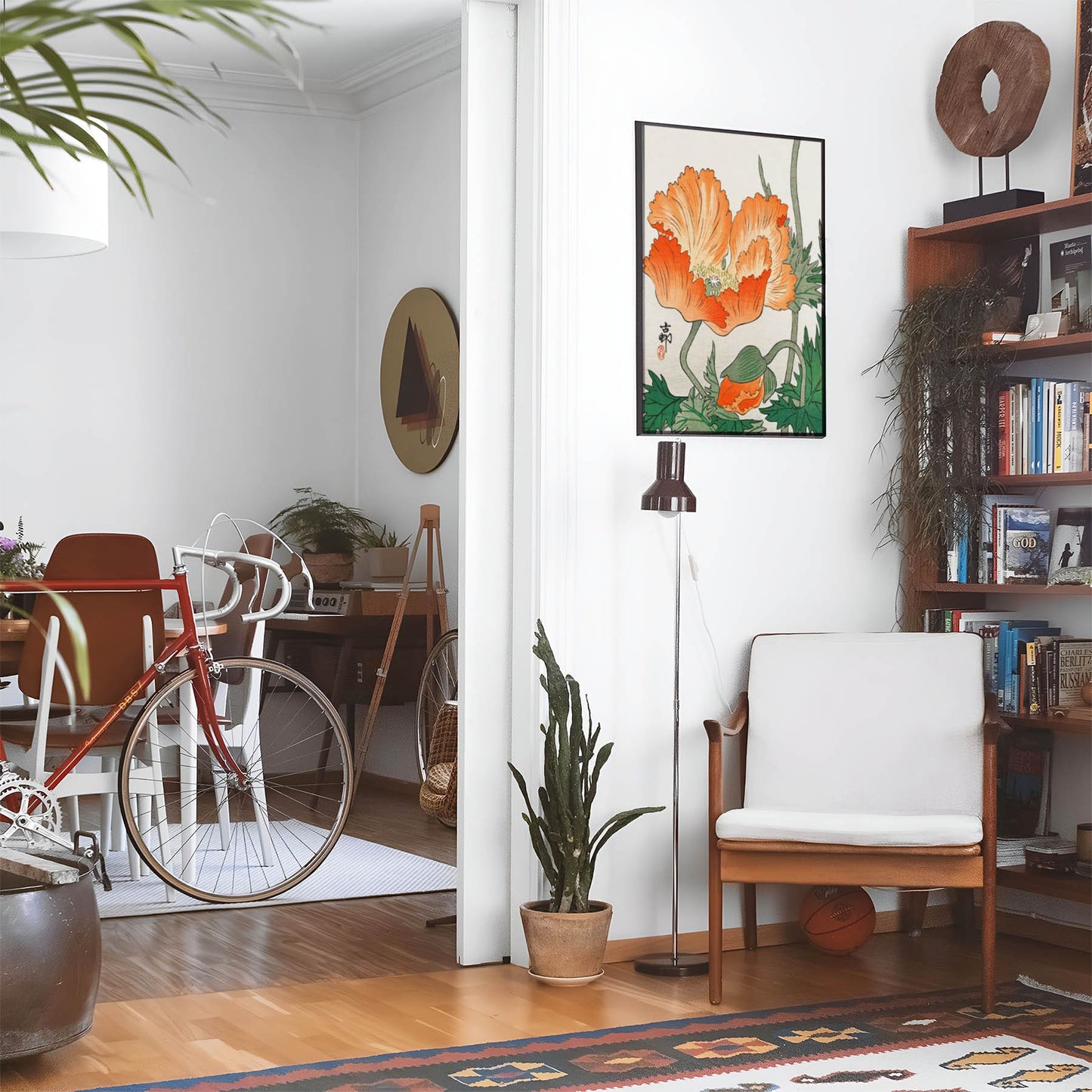 Living space with a black leather couch and table with a plant and books below a staircase featuring a framed picture of Uplifting Floral