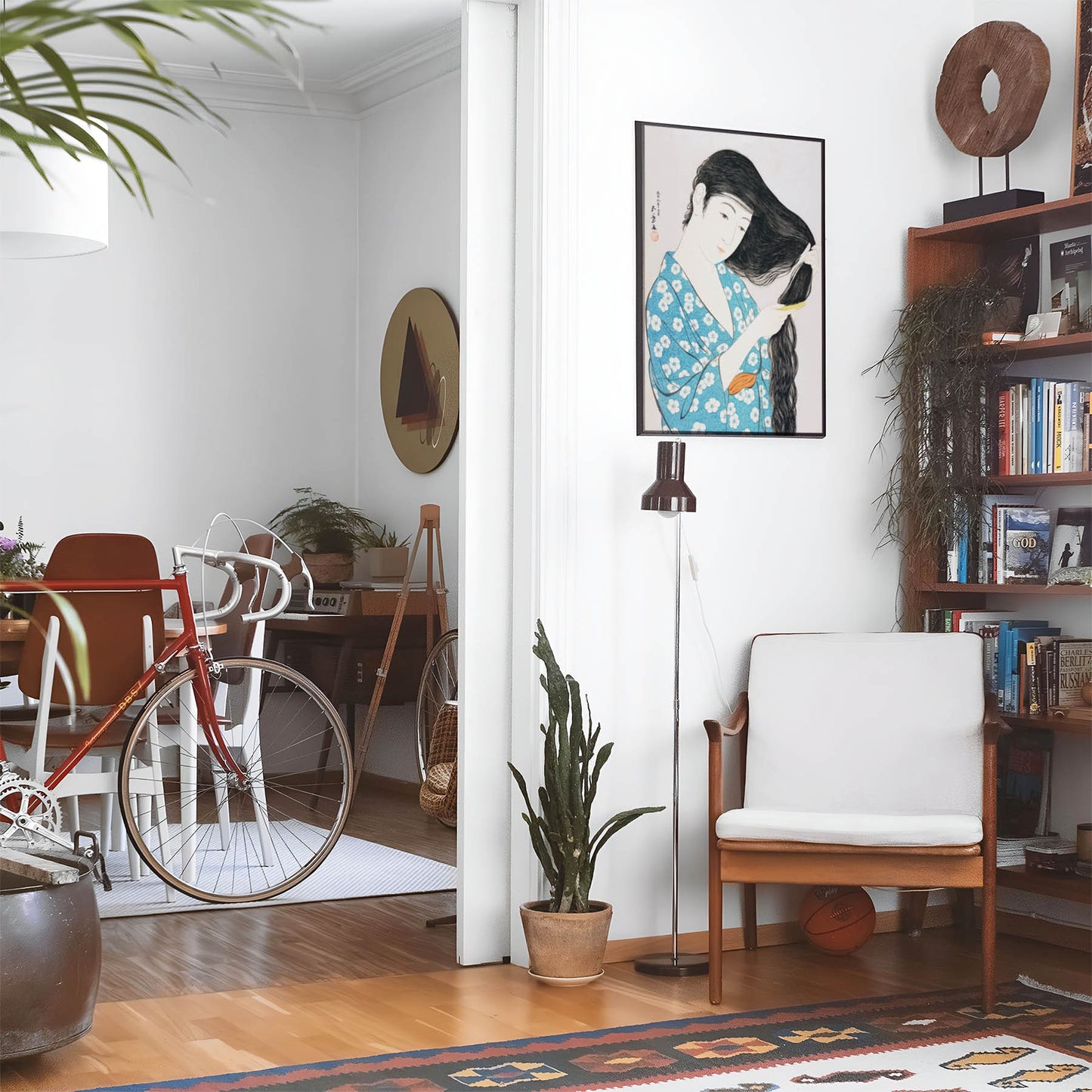 Eclectic living room with a road bike, bookshelf and house plants that features framed artwork of a Blue Flower Kimono above a chair and lamp