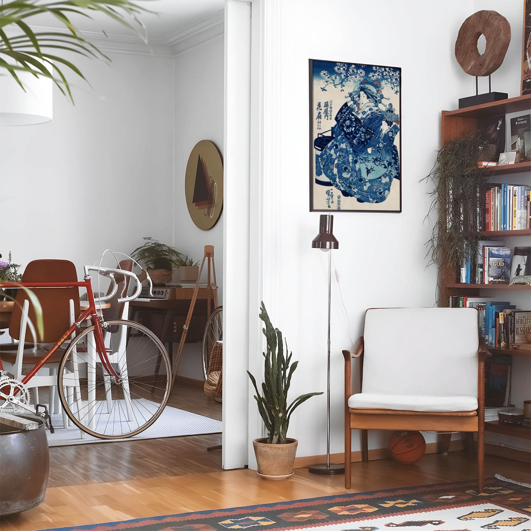 Eclectic living room with a road bike, bookshelf and house plants that features framed artwork of a Geisha in a Blue Kimono above a chair and lamp