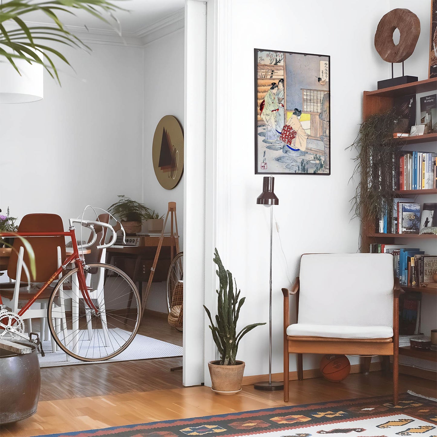 Eclectic living room with a road bike, bookshelf and house plants that features framed artwork of a Light and Minimalist Woodblock above a chair and lamp