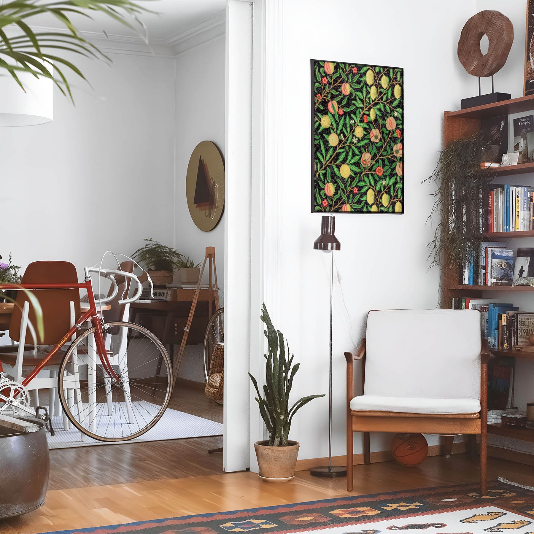 Eclectic living room with a road bike, bookshelf and house plants that features framed artwork of a Plants and Citrus above a chair and lamp