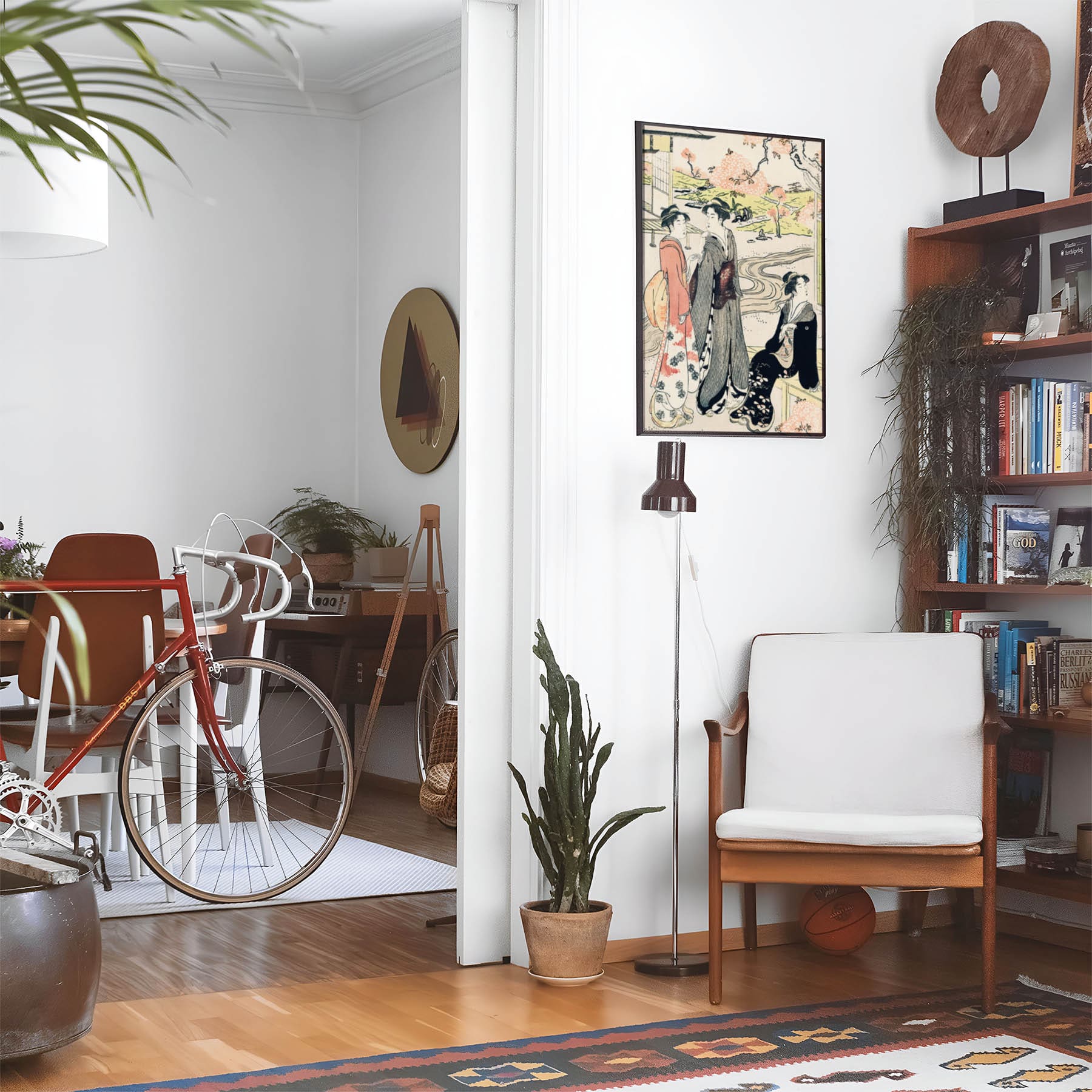 Eclectic living room with a road bike, bookshelf and house plants that features framed artwork of a Women in a Spring Landscape above a chair and lamp