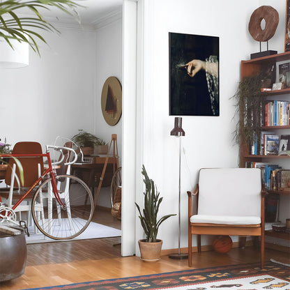 Eclectic living room with a road bike, bookshelf and house plants that features framed artwork of a Gothic Antique above a chair and lamp