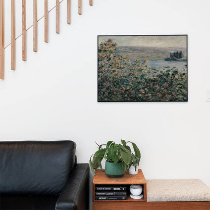 Living space with a black leather couch and table with a plant and books below a staircase featuring a framed picture of Green, Pink and Red Flowers