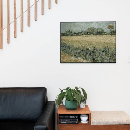 Living space with a black leather couch and table with a plant and books below a staircase featuring a framed picture of Peaceful Field