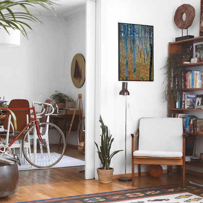 Eclectic living room with a road bike, bookshelf and house plants that features framed artwork of a Forest of Trees above a chair and lamp