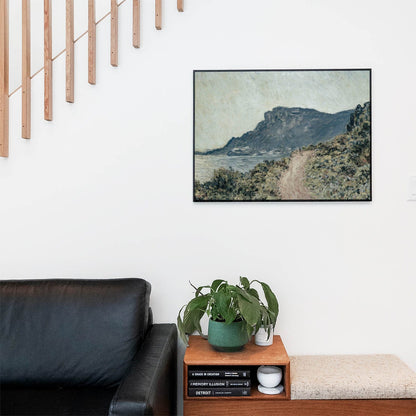 Living space with a black leather couch and table with a plant and books below a staircase featuring a framed picture of Pathway on the Seaside