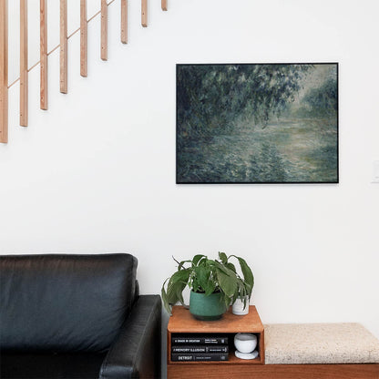 Living space with a black leather couch and table with a plant and books below a staircase featuring a framed picture of Relaxing Landscape