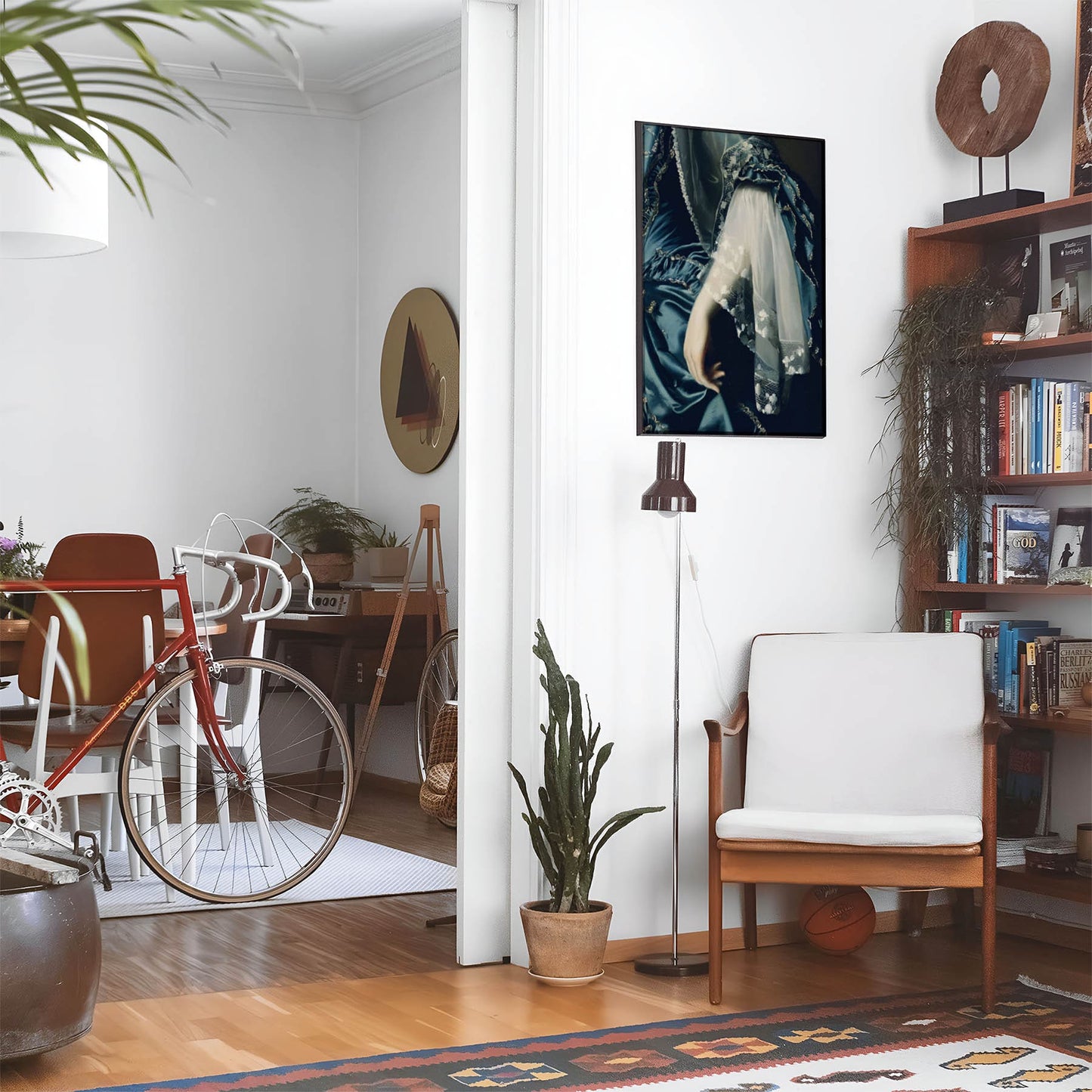 Eclectic living room with a road bike, bookshelf and house plants that features framed artwork of a Aesthetic Sapphire Blue Dress above a chair and lamp
