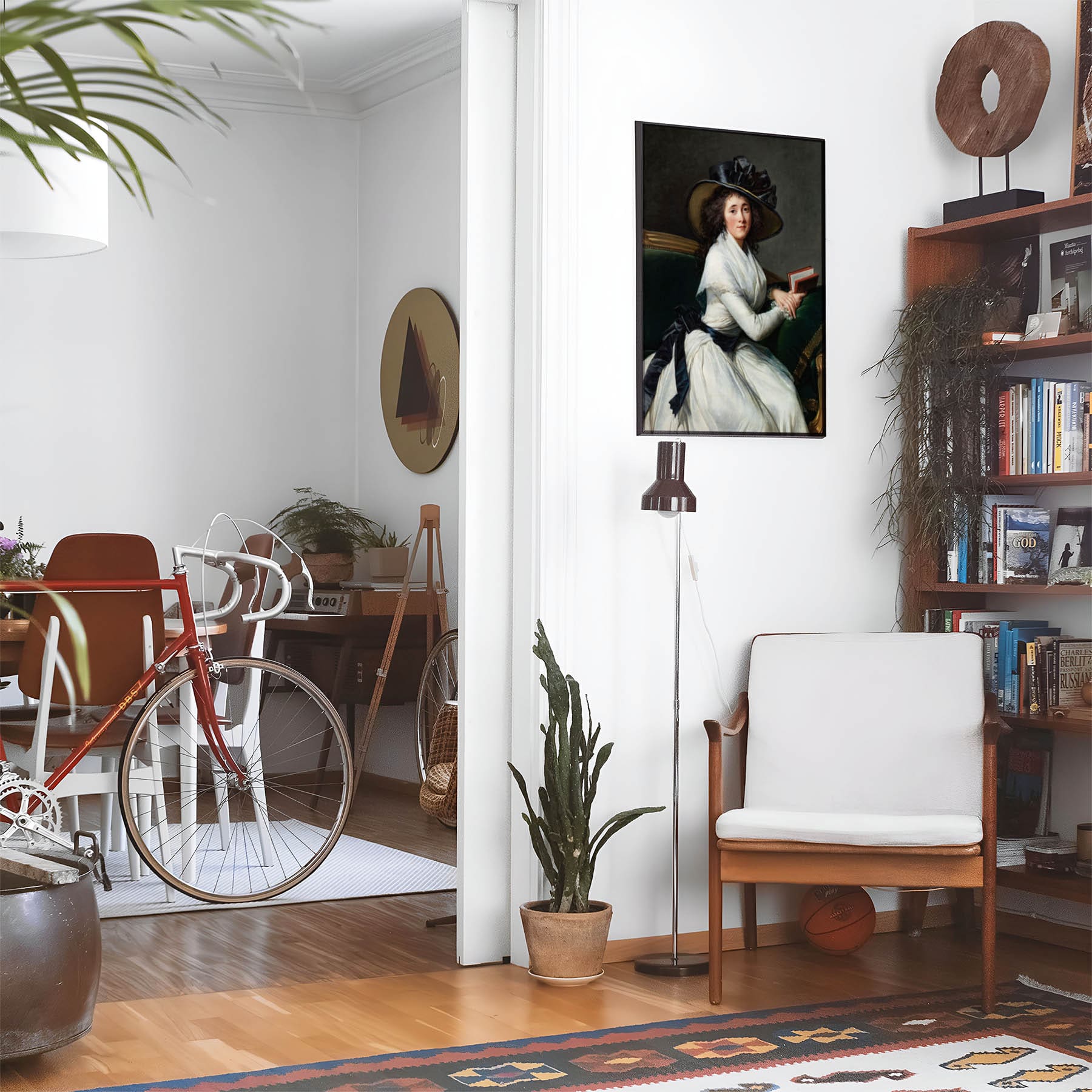 Living space with a black leather couch and table with a plant and books below a staircase featuring a framed picture of Woman in a Back Hat