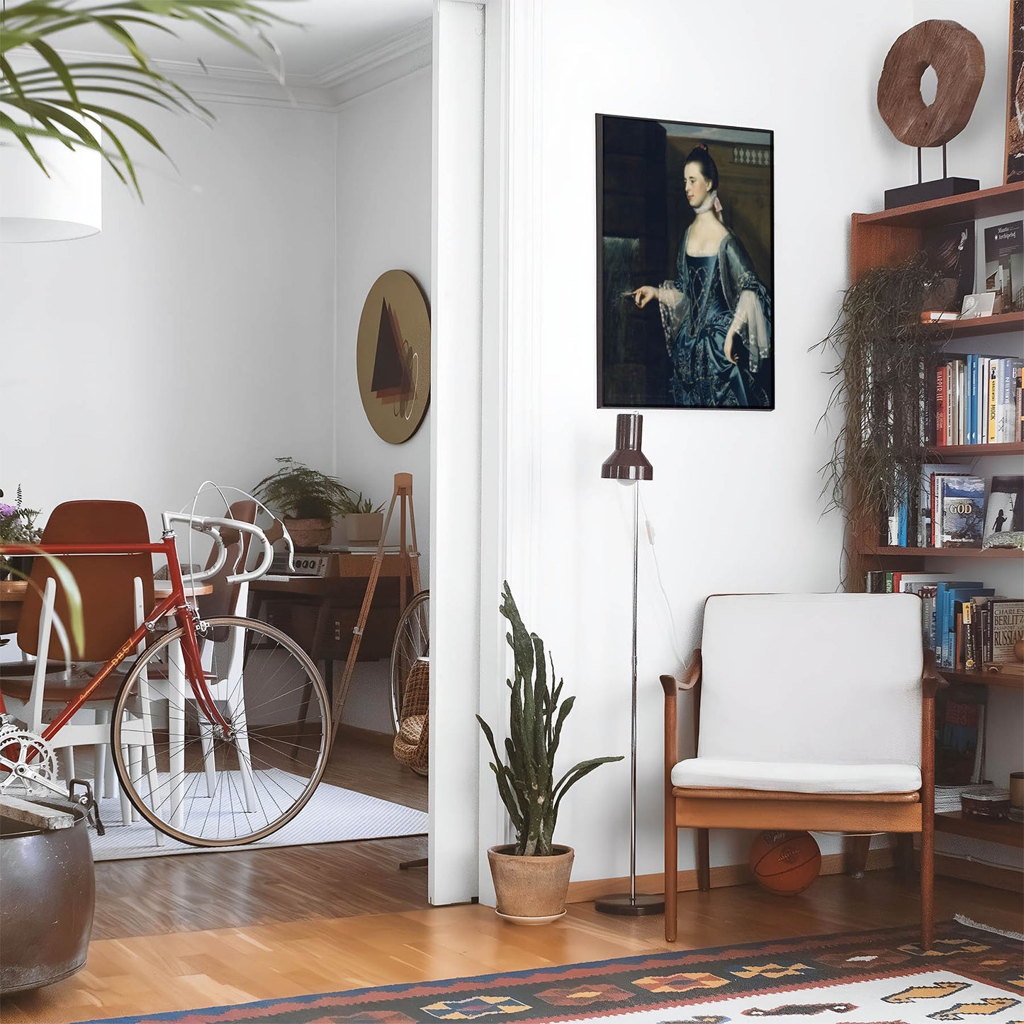 Eclectic living room with a road bike, bookshelf and house plants that features framed artwork of a Aesthetic Sapphire Blue Dress above a chair and lamp