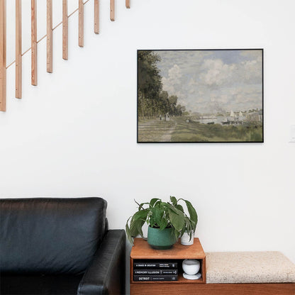 Living space with a black leather couch and table with a plant and books below a staircase featuring a framed picture of Walking by the Shore