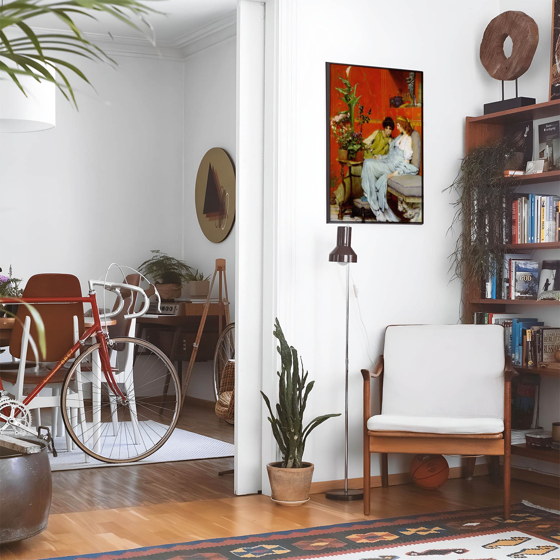 Eclectic living room with a road bike, bookshelf and house plants that features framed artwork of a Friendships and Lovers above a chair and lamp