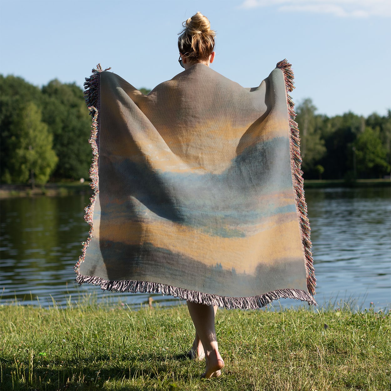 Sun in the Clouds Woven Throw Blanket Held on a Woman's Back Outside