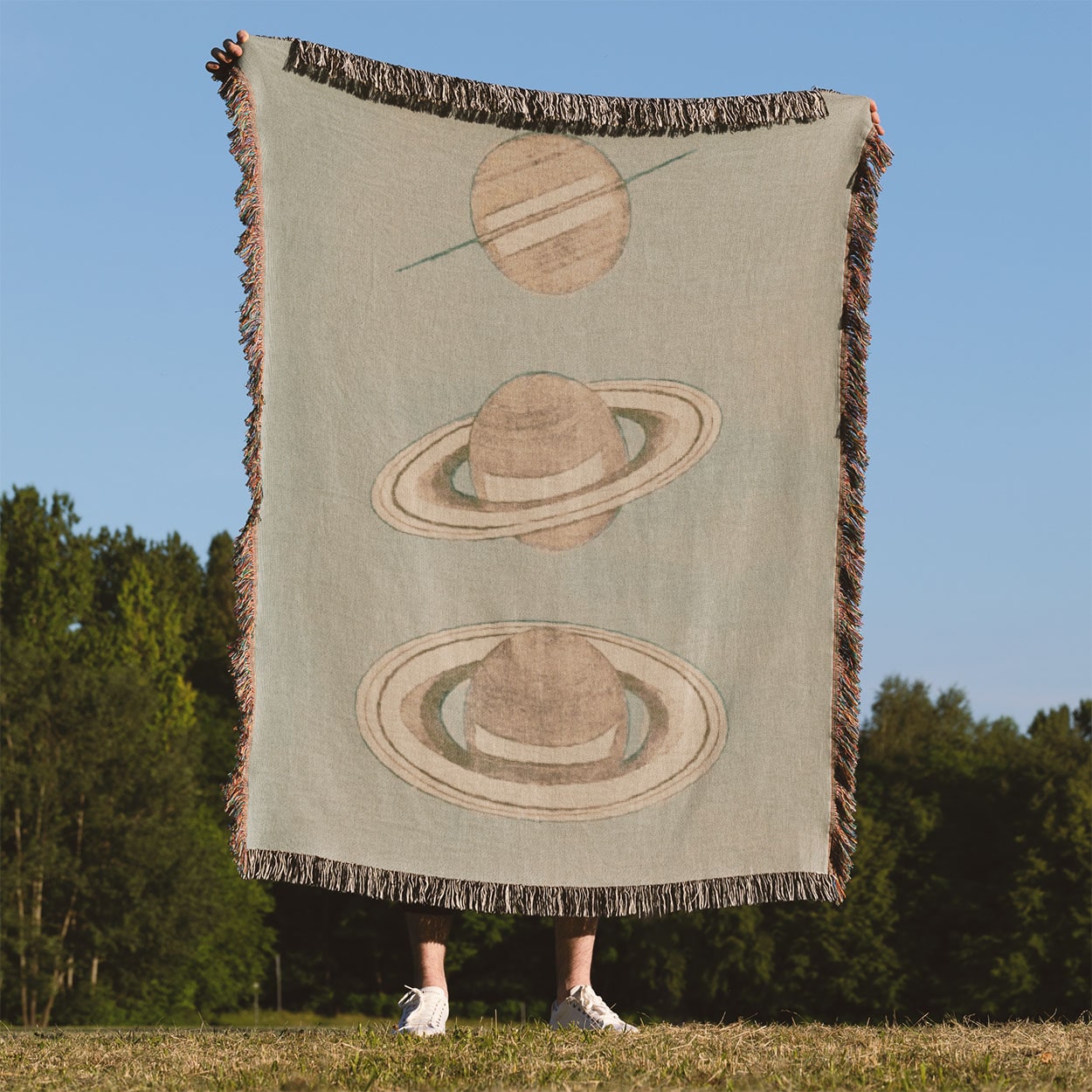 The Rings of Saturn Woven Blanket Held Up Outside