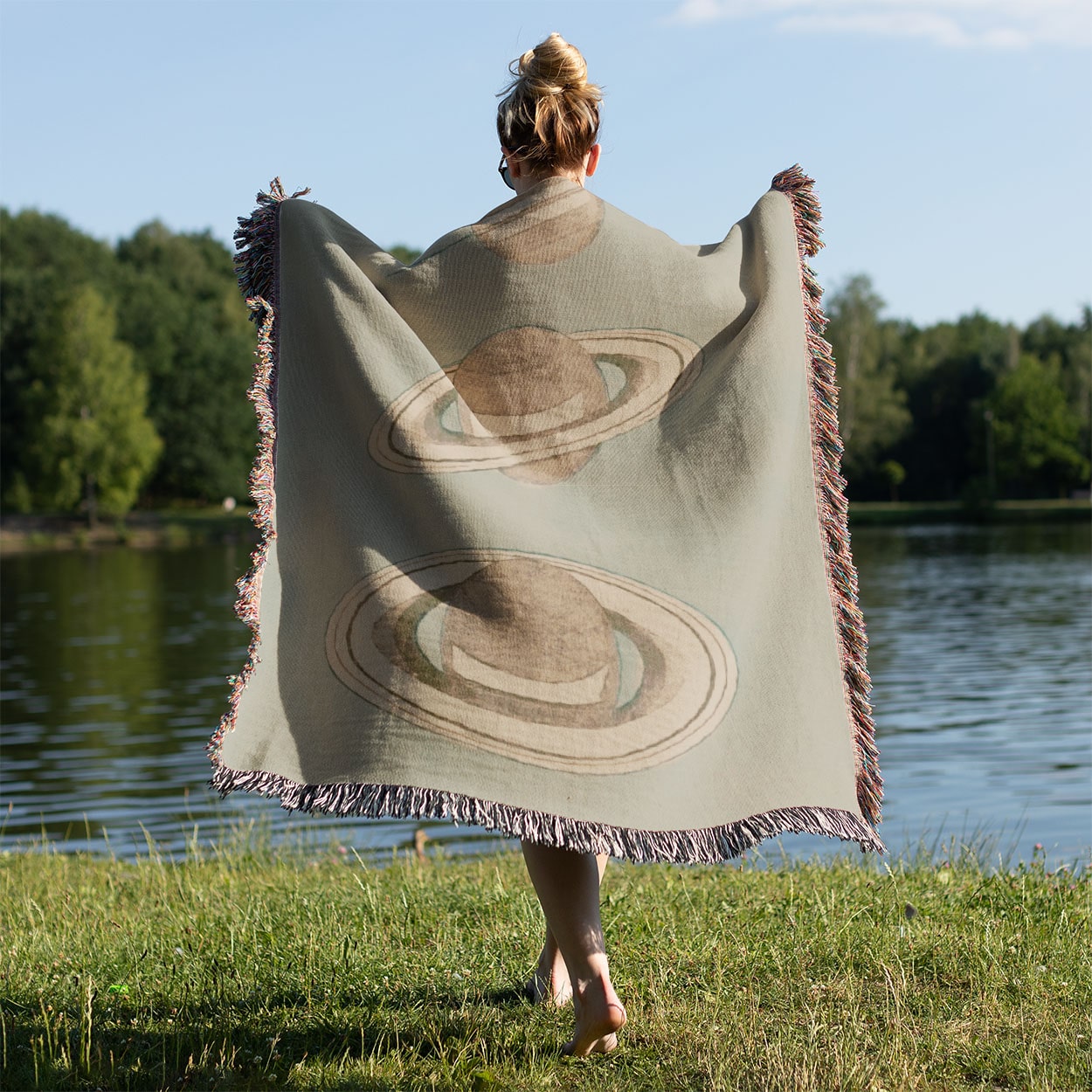 The Rings of Saturn Woven Blanket Held on a Woman's Back Outside