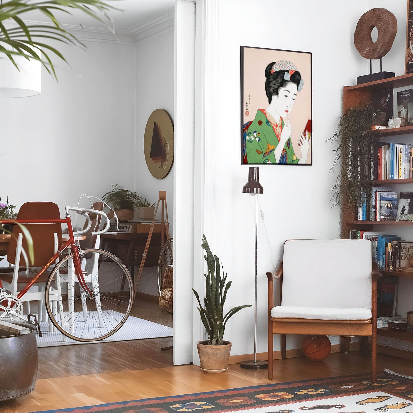 Eclectic living room with a road bike, bookshelf and house plants that features framed artwork of a Geisha Applying Lipstick above a chair and lamp