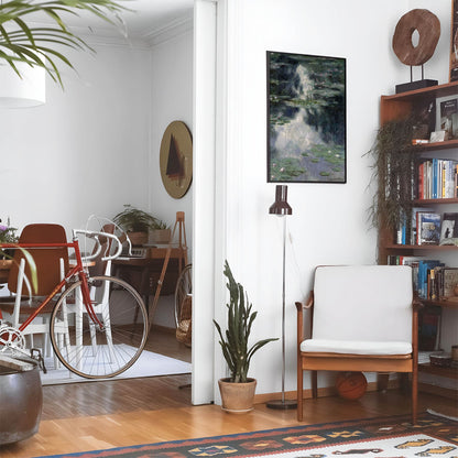Eclectic living room with a road bike, bookshelf and house plants that features framed artwork of a Muted Water with Lillies above a chair and lamp