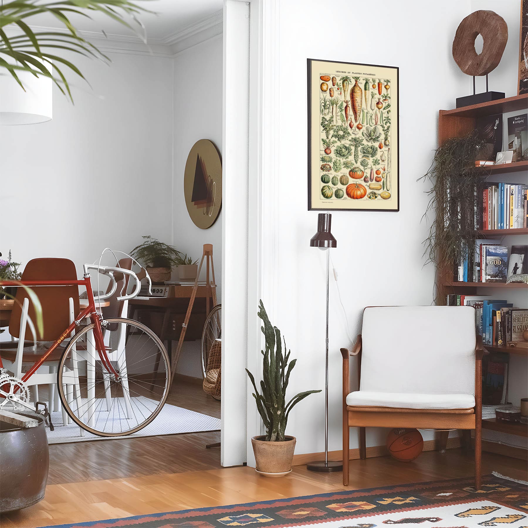 Eclectic living room with a road bike, bookshelf and house plants that features framed artwork of a Garden Vegetables above a chair and lamp