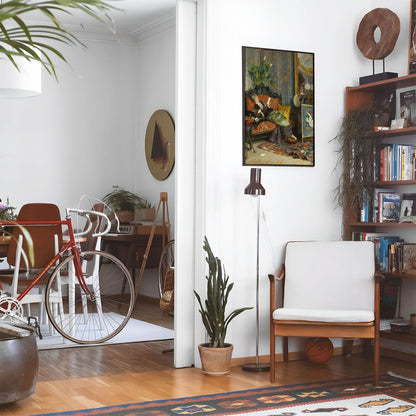 Eclectic living room with a road bike, bookshelf and house plants that features framed artwork of a Relaxing Reading above a chair and lamp