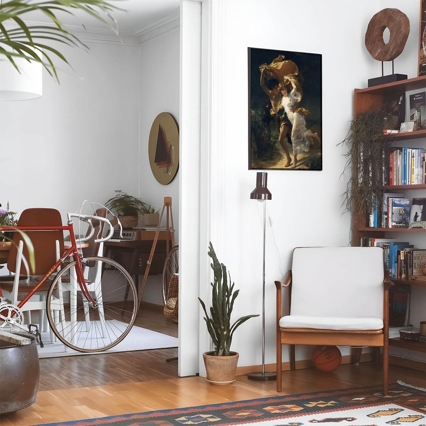 Eclectic living room with a road bike, bookshelf and house plants that features framed artwork of a Romance above a chair and lamp