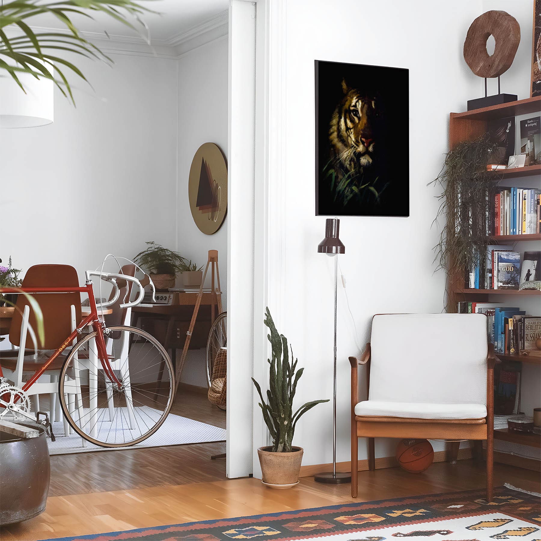 Eclectic living room with a road bike, bookshelf and house plants that features framed artwork of a Dark Tiger above a chair and lamp