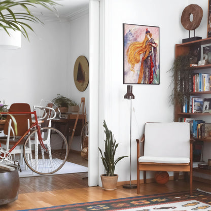 Eclectic living room with a road bike, bookshelf and house plants that features framed artwork of a The Story of Rapunzel above a chair and lamp