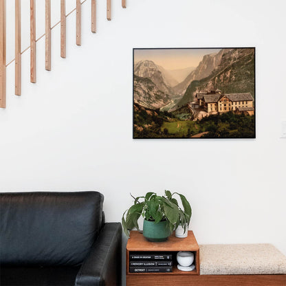 Living space with a black leather couch and table with a plant and books below a staircase featuring a framed picture of Mountains and River