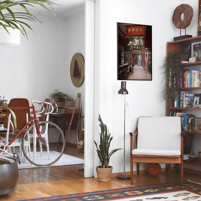 Eclectic living room with a road bike, bookshelf and house plants that features framed artwork of a Vintage Chinese Shop above a chair and lamp