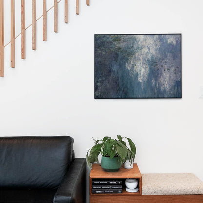 Living space with a black leather couch and table with a plant and books below a staircase featuring a framed picture of Aesthetic Blue