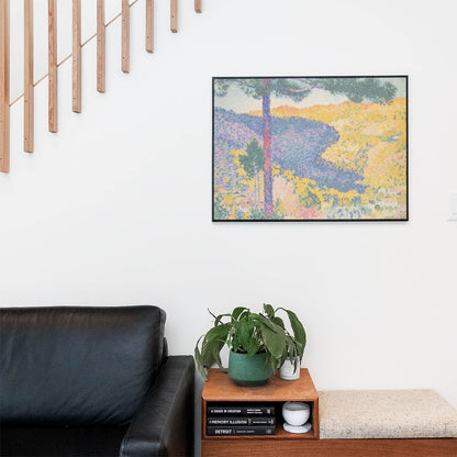 Living space with a black leather couch and table with a plant and books below a staircase featuring a framed picture of Beautiful Nature