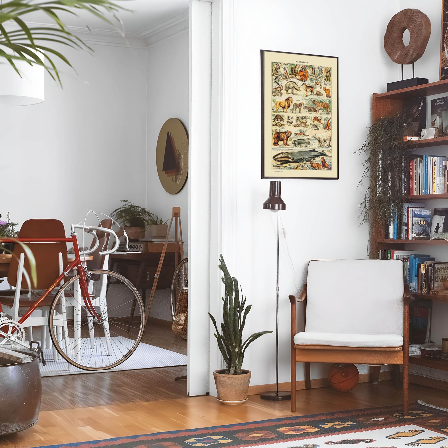 Living space with a black leather couch and table with a plant and books below a staircase featuring a framed picture of All Sorts of Mammals