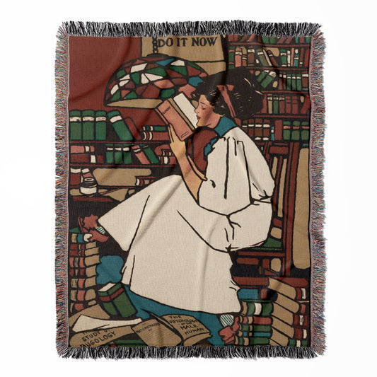 Woman Reading woven throw blanket, made of 100% cotton, delivering a soft and cozy texture with a reading on a stack of books theme for home decor.